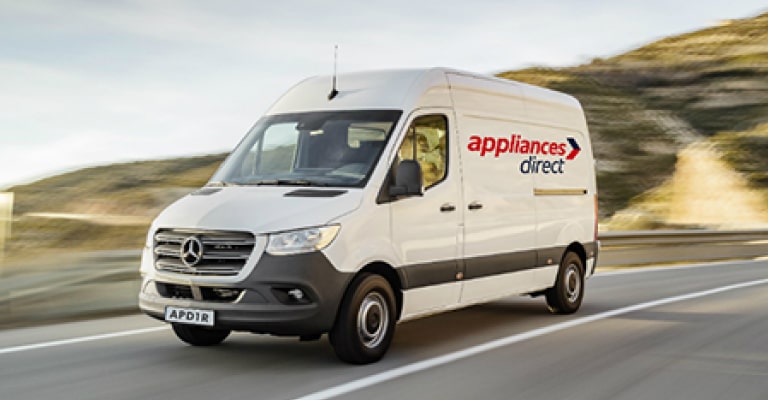 A delivery driver carrying a boxed appliance to a customer's door.